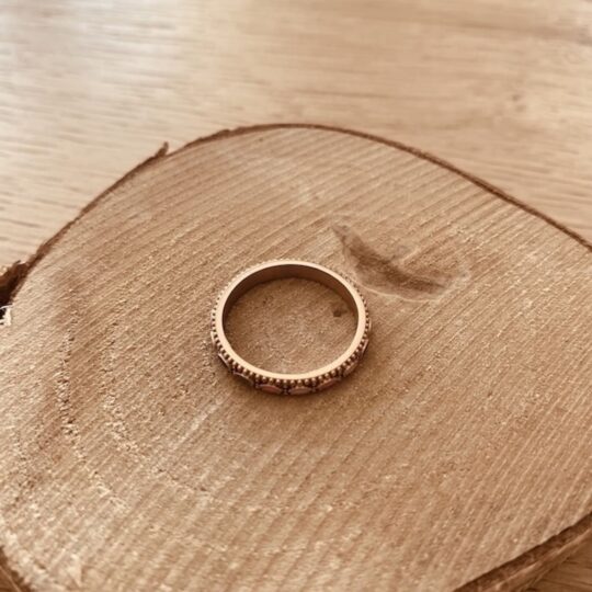 Bague anneau fin pour femme en acier inoxydable or rose avec motifs navettes emailles bleu marine et rose pose sur bois